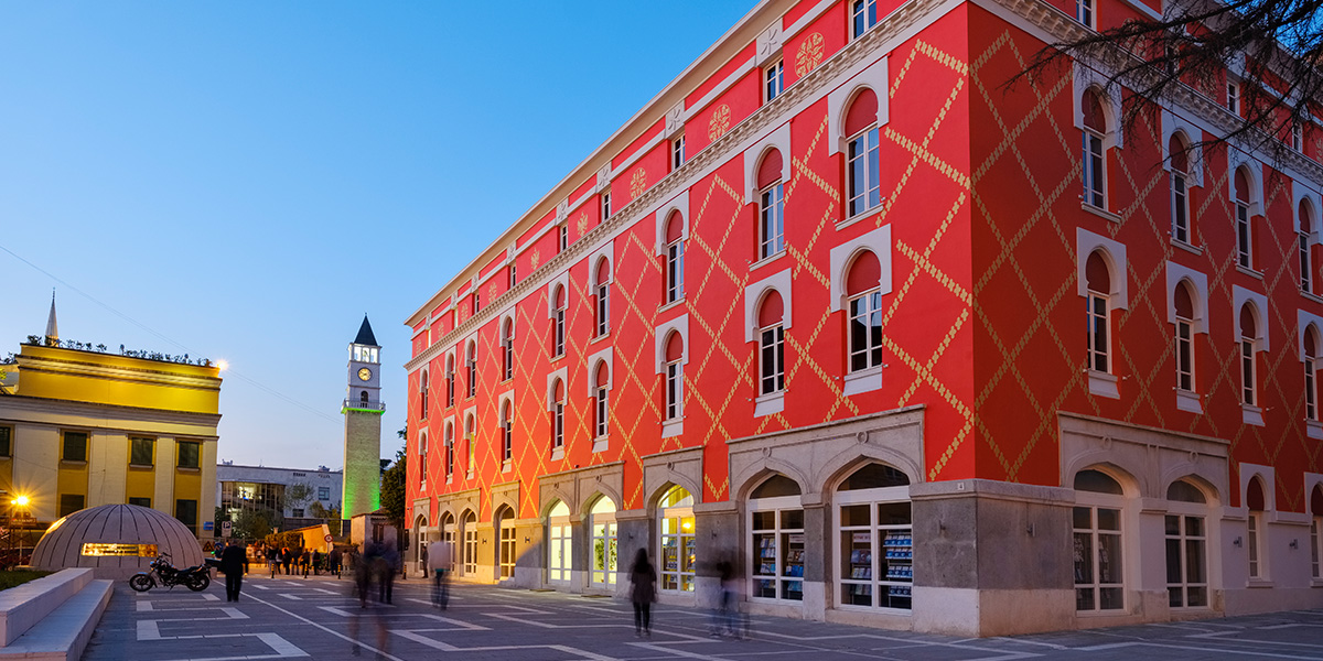 Bymiljø i Tirana med rød bygning og klokketårn