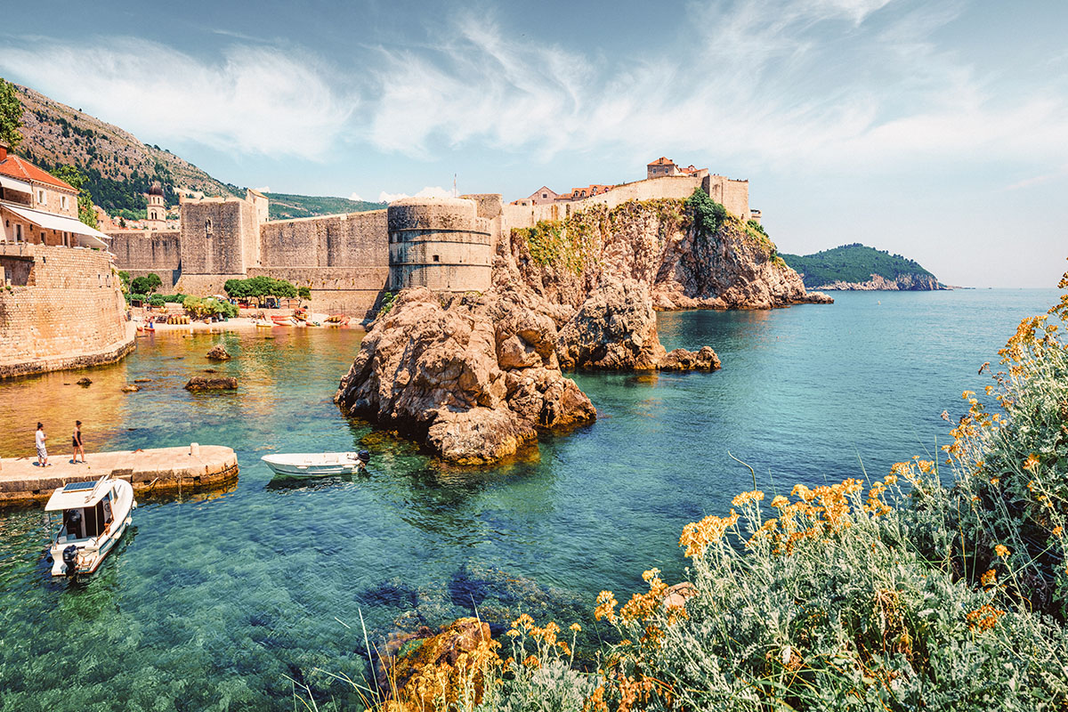 Dubrovnik bymur sett fra en bukt med krystallklart vann
