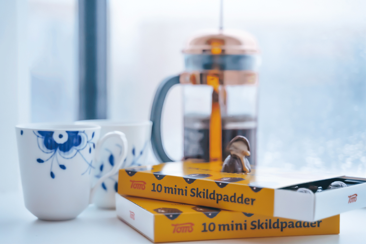 bilde av royal copenhagen kopp med blått blomstermotiv og to esker med 10 mini skilpadder. Det står en presskanne med kaffe i bakgrunnen. 