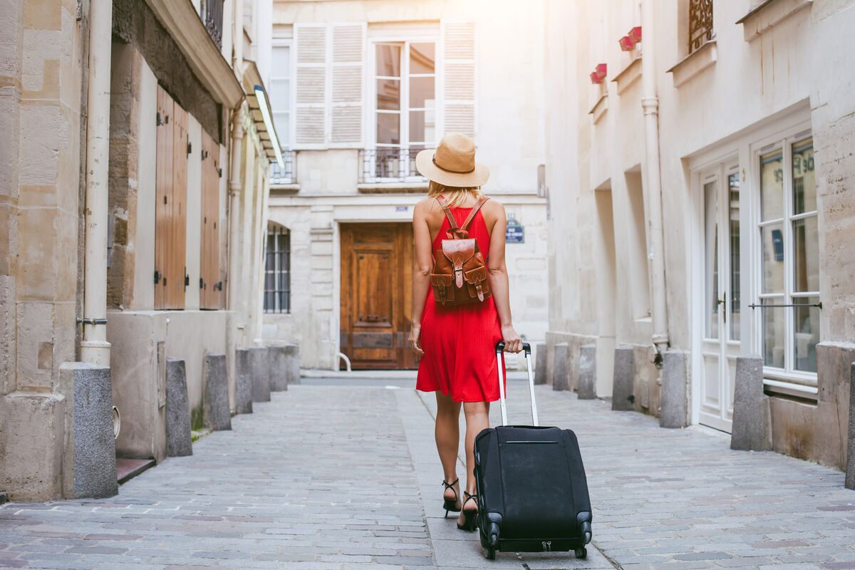 Woman in red dress pulling a suitcase