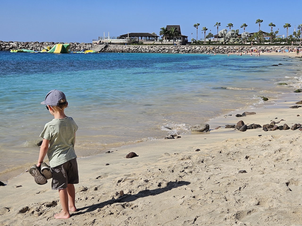 young boy standing on beach in cap and t shirt