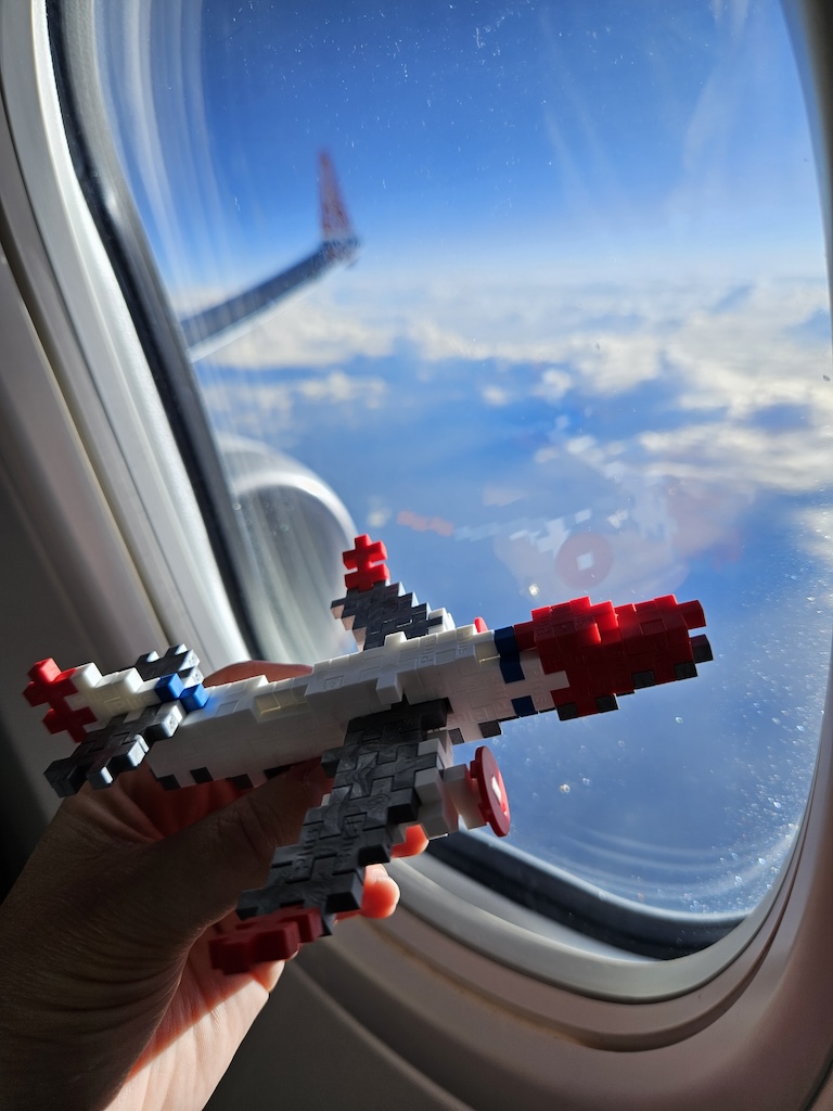 play airplane in front of the window of an actual airplane