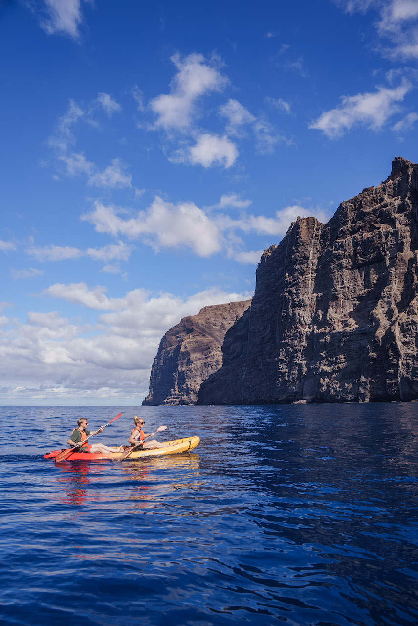 To mennesker padler i kayak under en enorm klippevegg