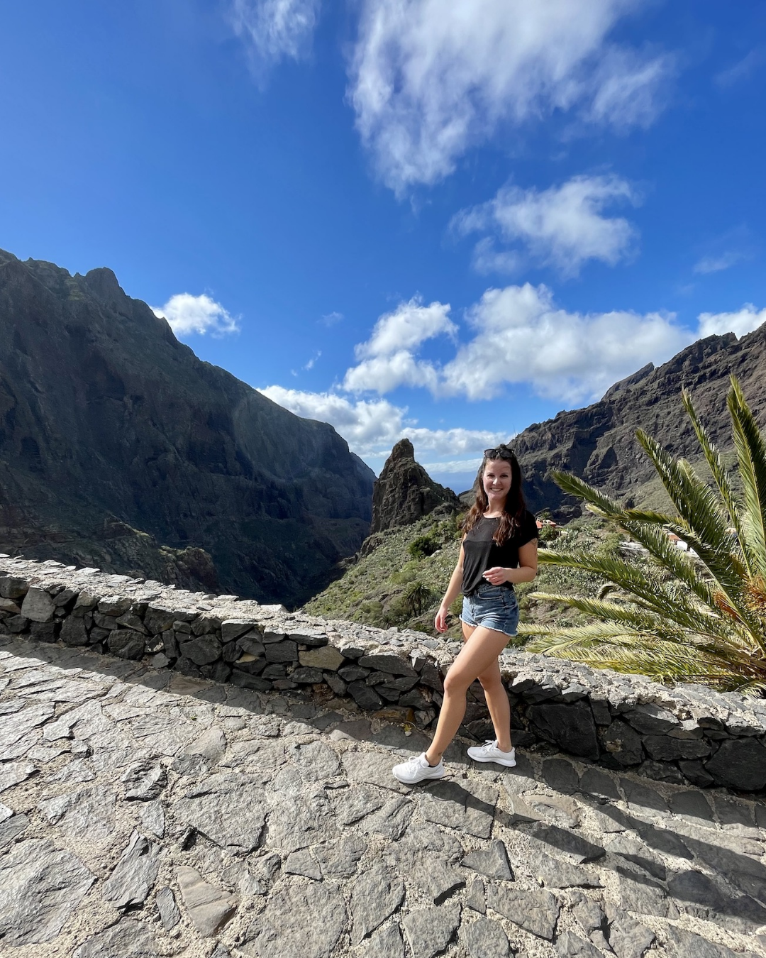 Off duty crew member poses in front of breathtaking viewpoint with mountains and ocean in background