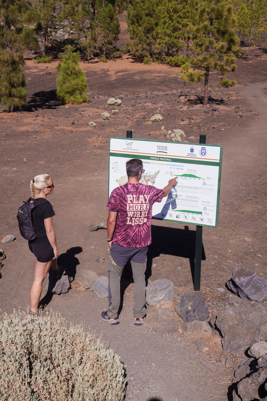 To mennesker ser på et skilt omhandlende Teide i et vulkansk landskap