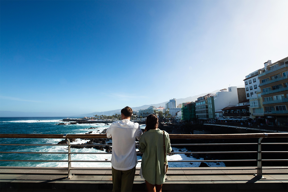 To mennesker ser utover havet rett ved en ferieby på Tenerife
