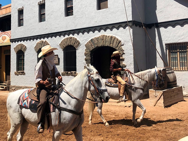 två cowboys på vita hästar i en stad i västernstil