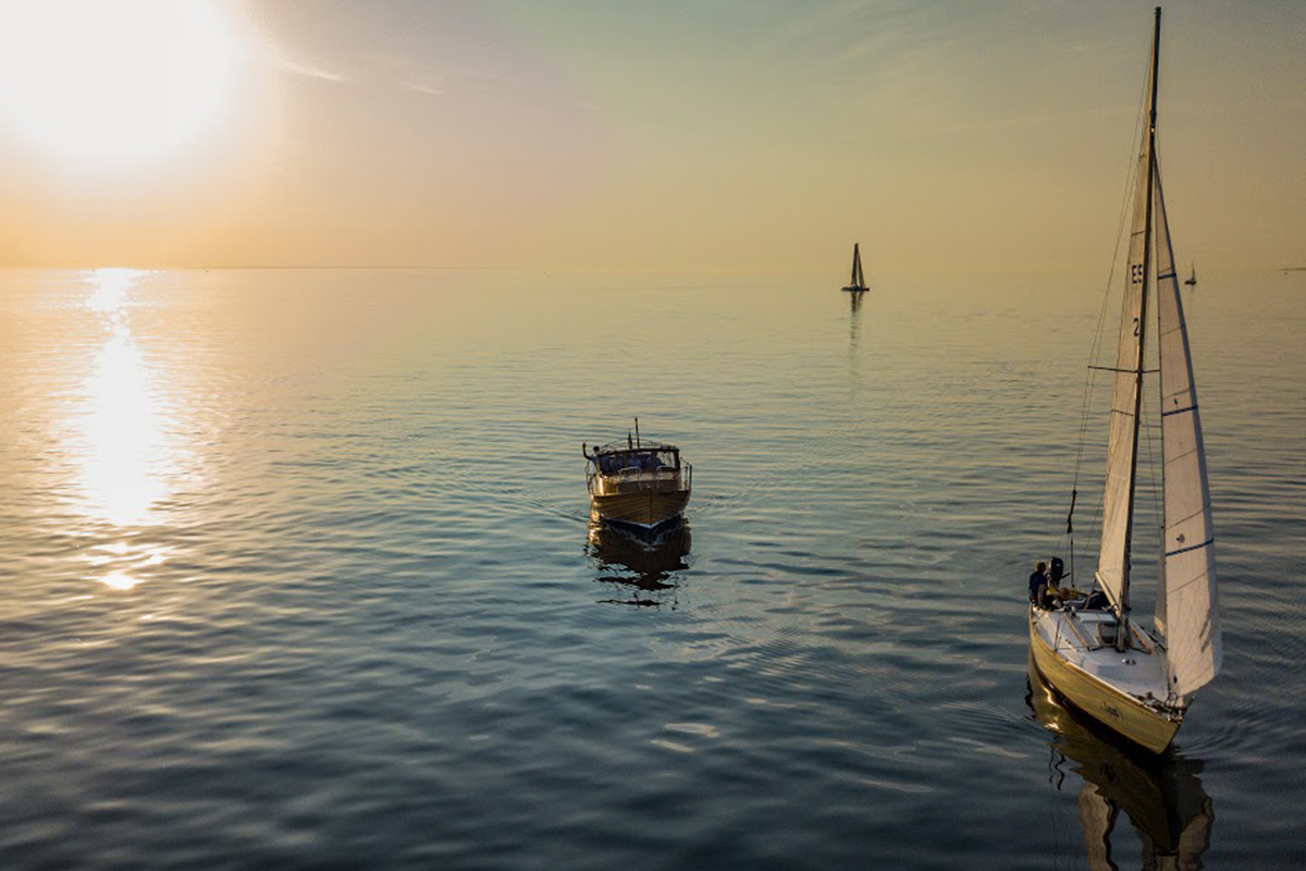 En segelbåt och en motorbåt till havs vid solnedgång