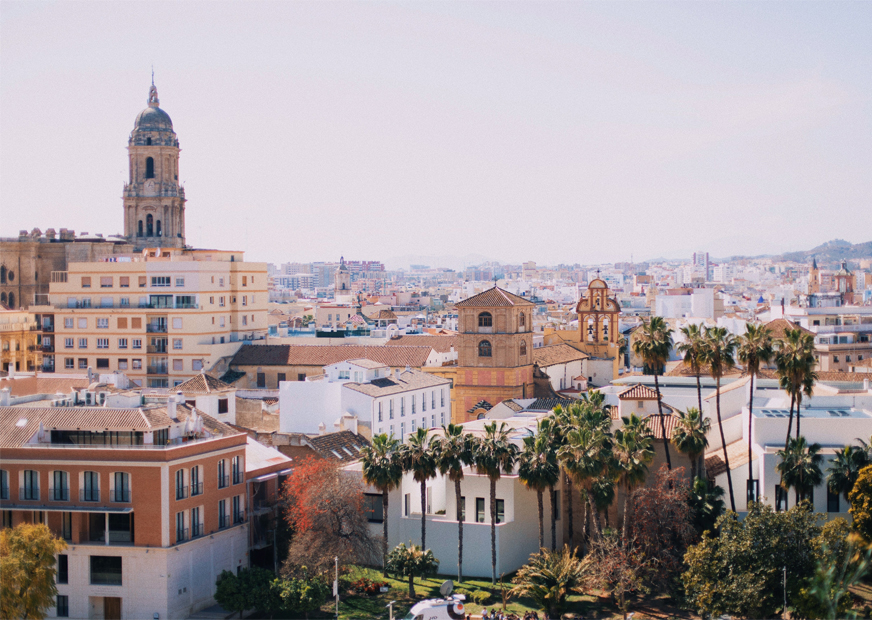 Malage skyline with tall church tower, palm trees and misty weather