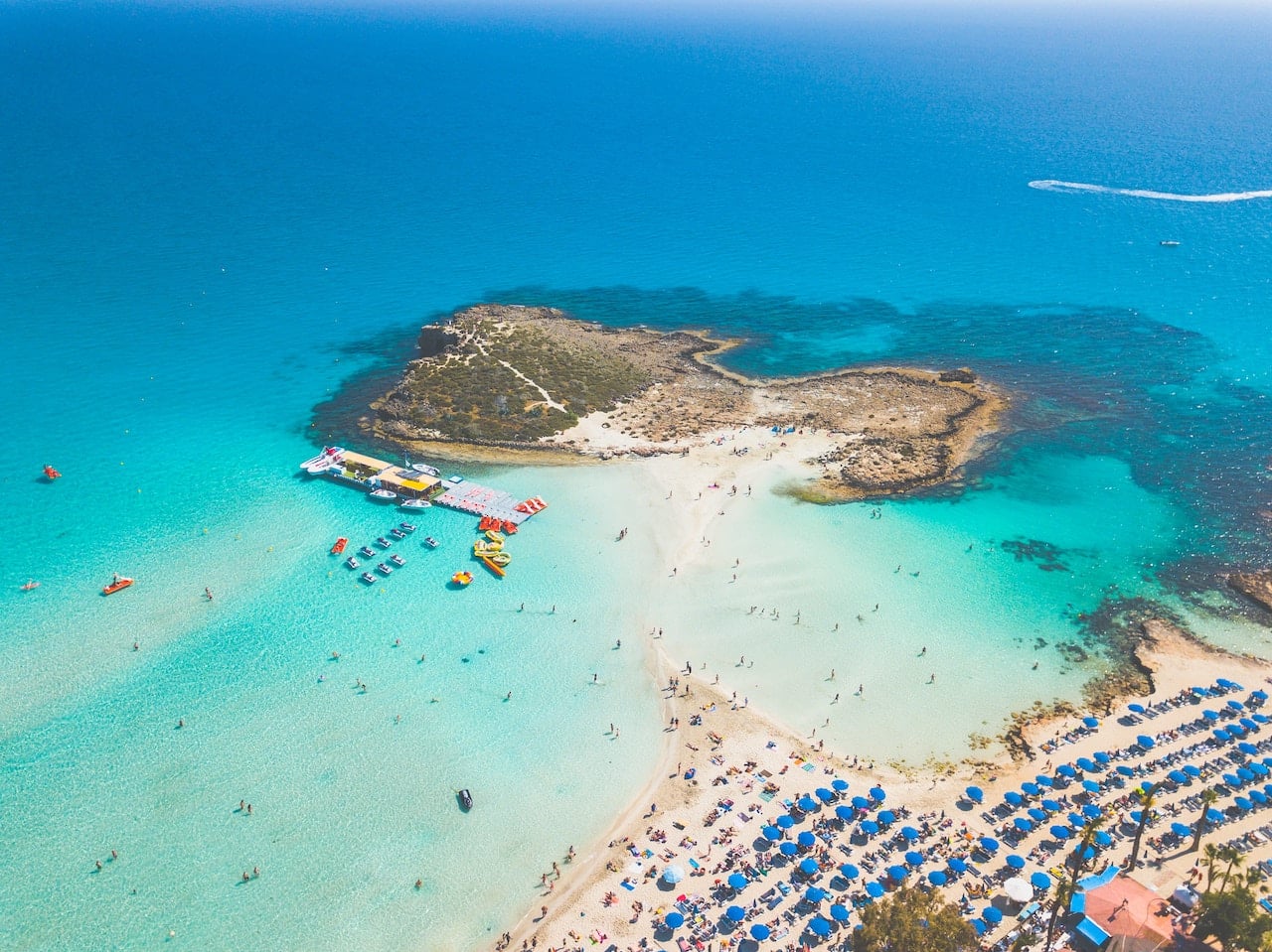 Small island only reachable by white sand, surrounded by turquiose ocean. 