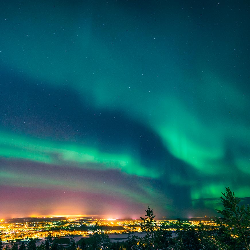 Nordlyset dækker hele himlen. En smule af solnedgangen i horisonten.