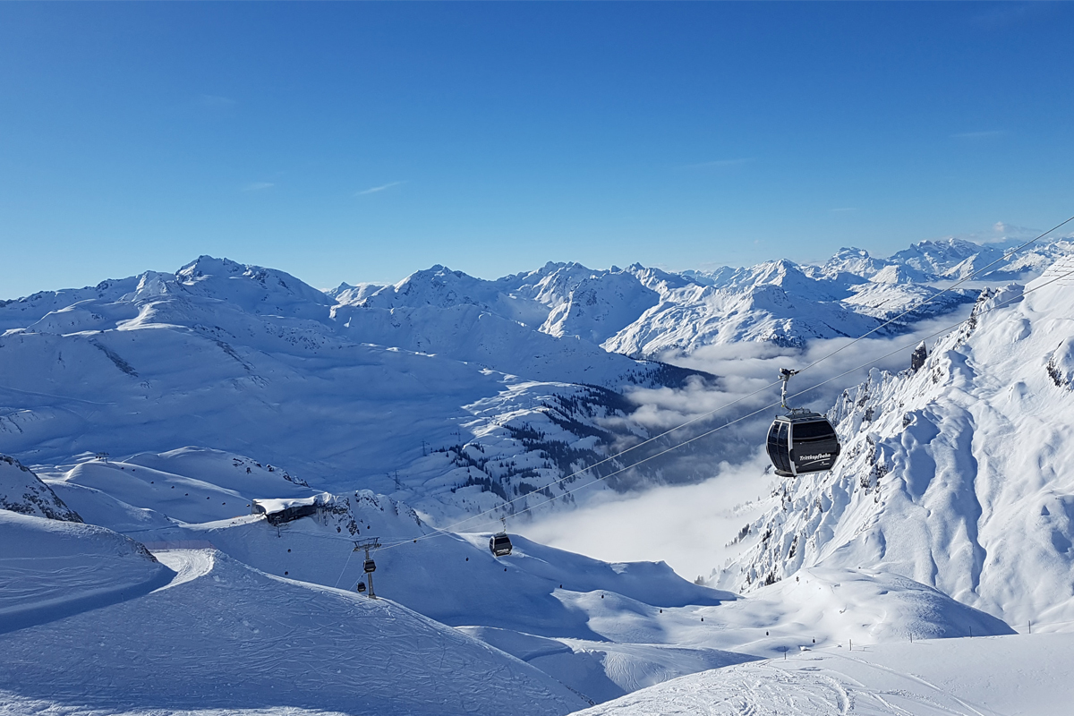 hvite skibakker og hvite fjelltopper med blå himmel