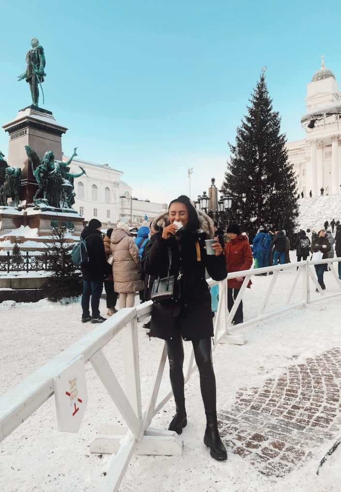 Woman in black clothes smiling standing infront of a Christmas market
