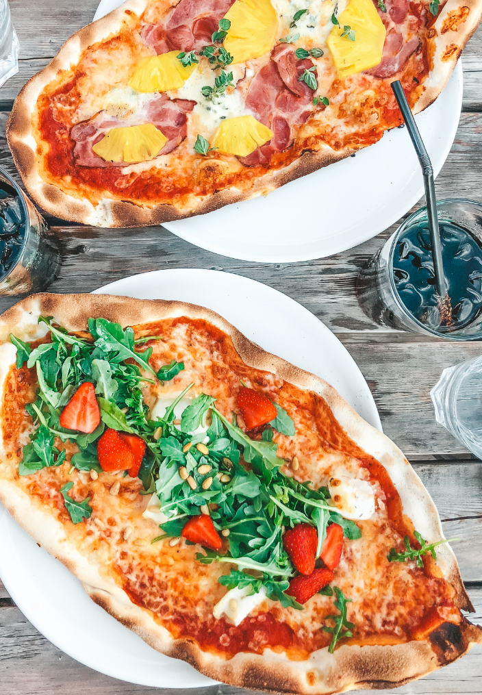 oval shaped pizzas with toppings such as pineapple, pine seeds and strawberries
