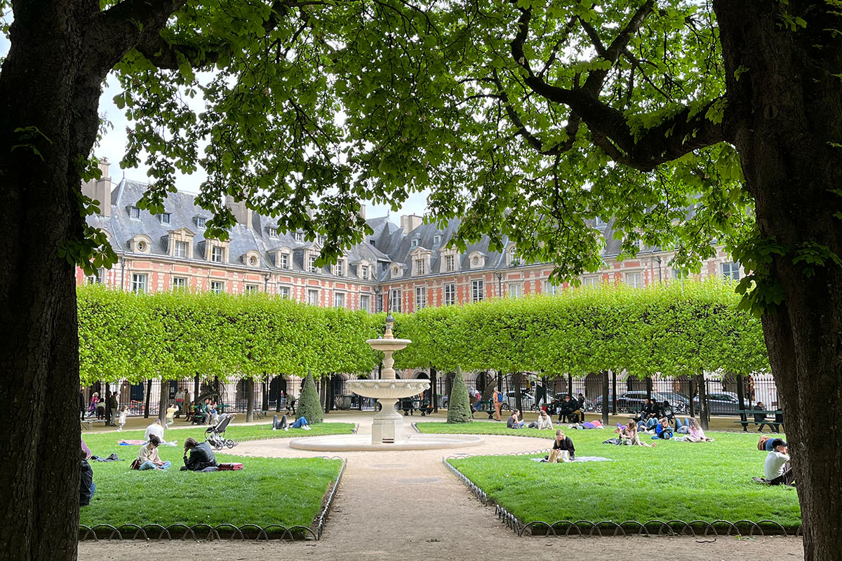 Place des Vosges - en kvadratisk park i Paris med flotte trær rundt parken.