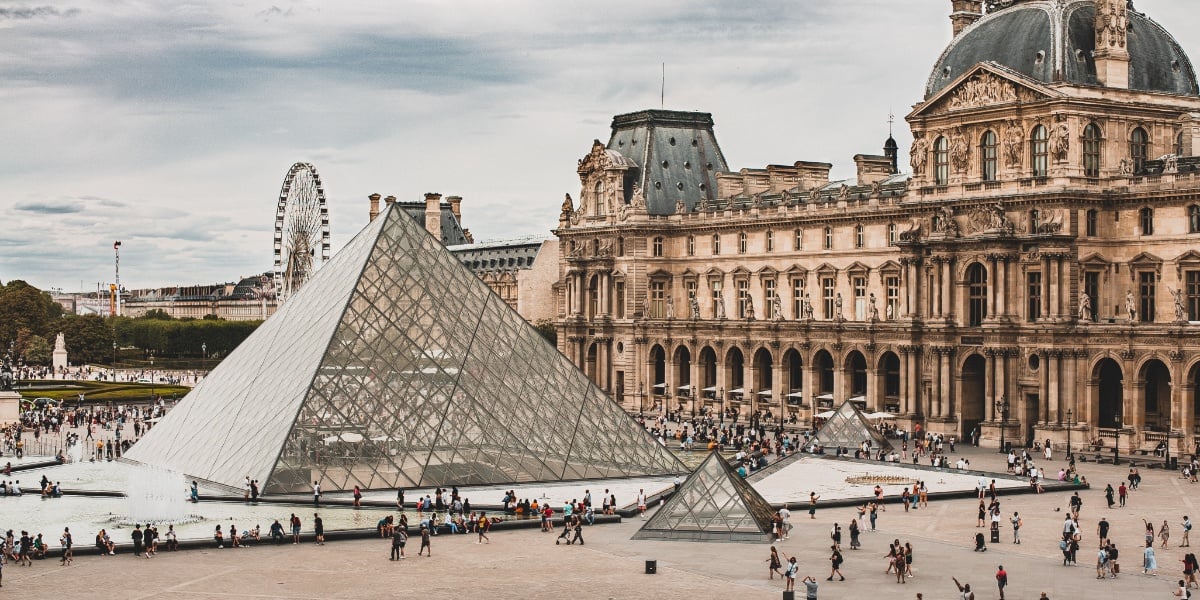Louvre i Paris med glasspyramiden i front og litt av museet bak