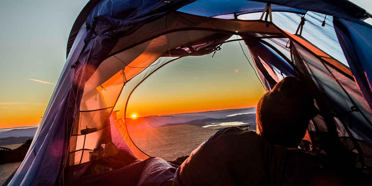 Man watching the sunset from his tent