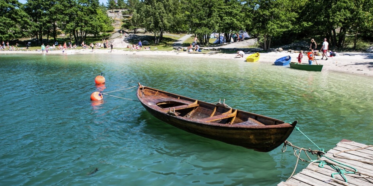 Hvid sandstrand med mennesker og en båd