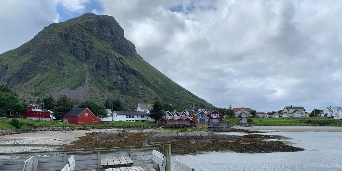 En fjelltopp med en liten bygd i forgrunnen