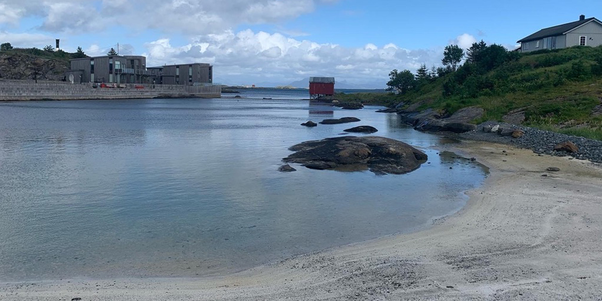 Hvit sandstrand i en liten bukt. 