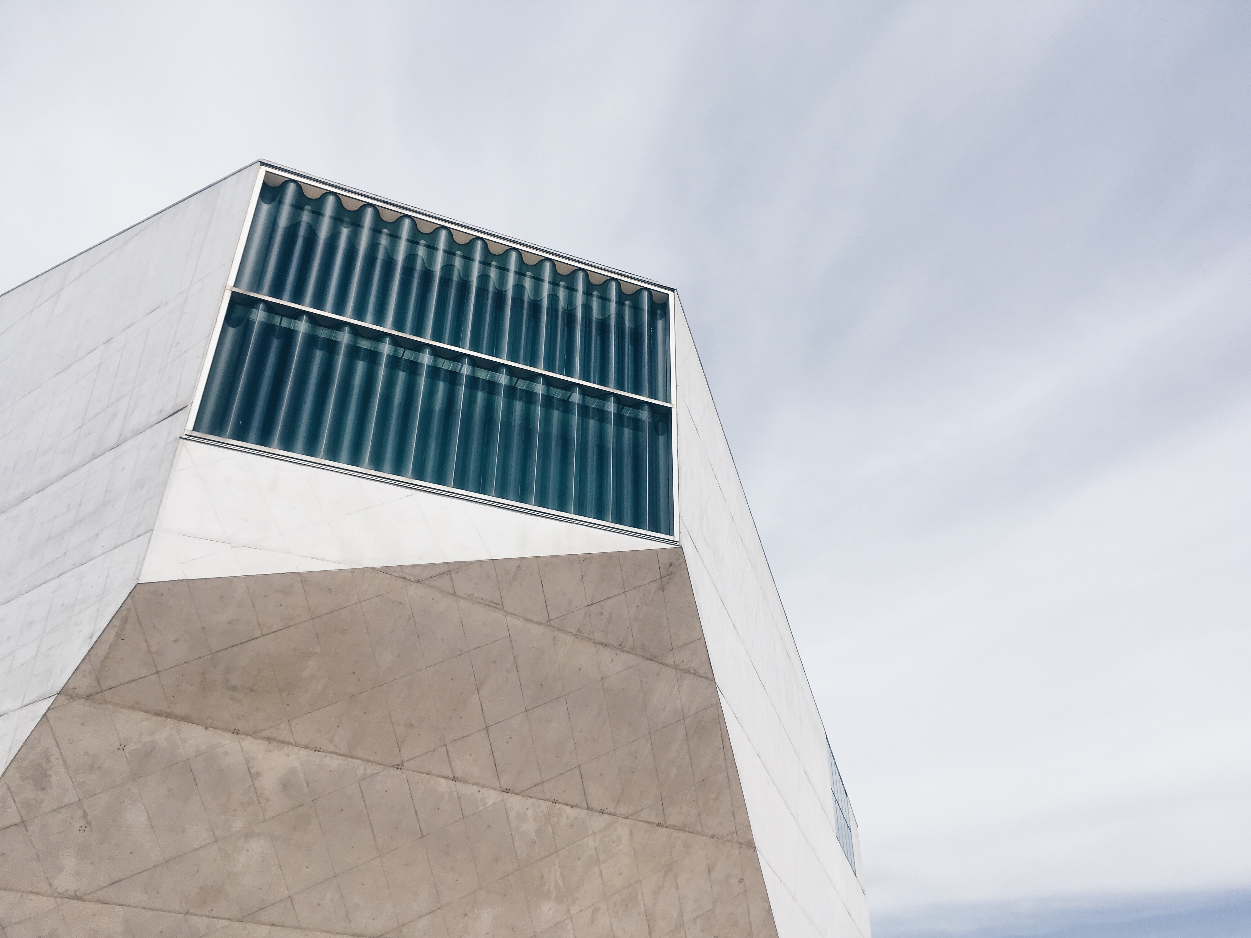 Modernistisk bygning i hvid marmor med vindue i bølget glas.