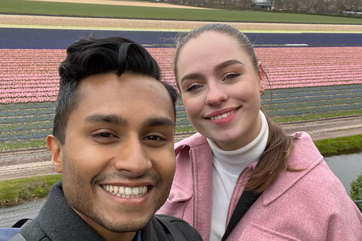 A young man and a young woman poses in front of a tulip field