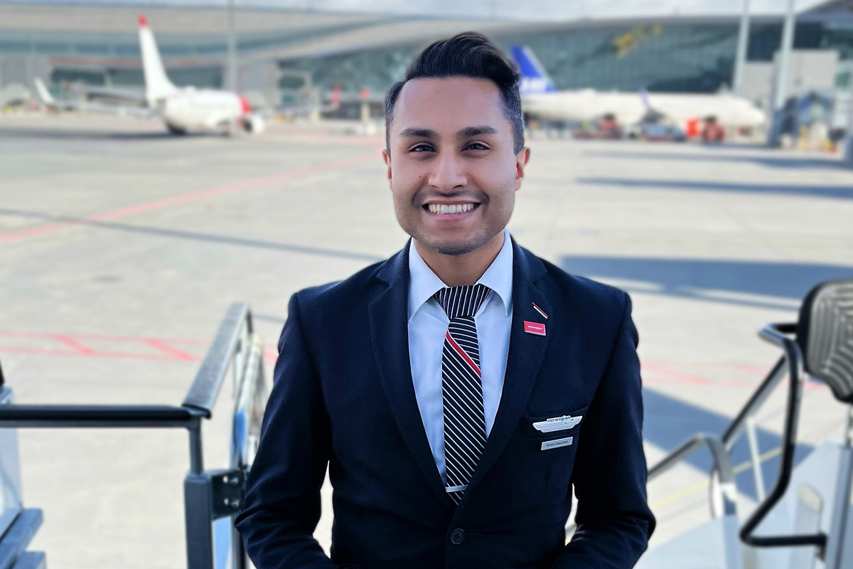 A cabin crew stands at the entrance of a plane