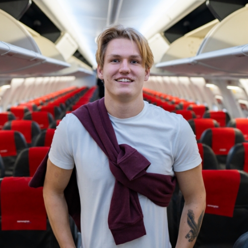 Young blonde man standing inside empty airplane