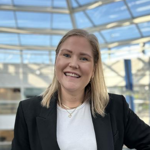 Blond woman wearing business casual. Smiling under glass roof