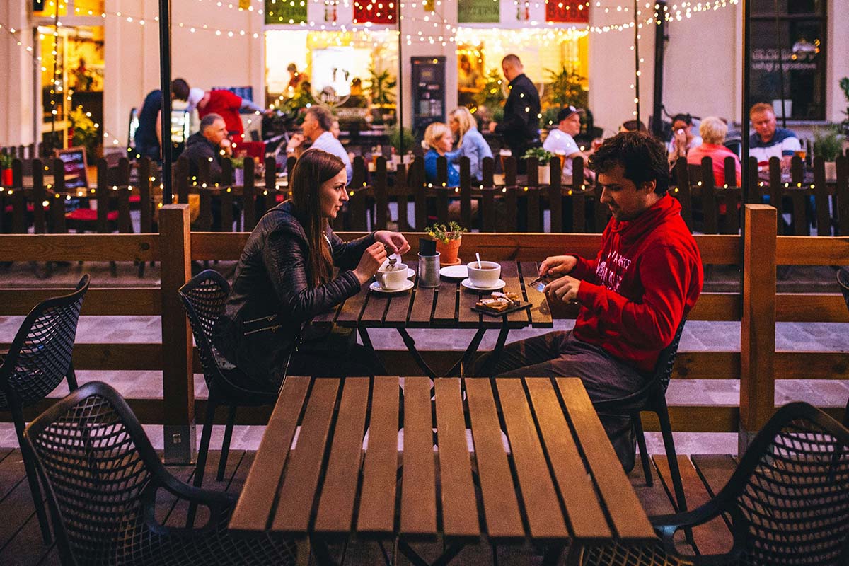 Et par sitter ved et bord og spiser på en utekafe