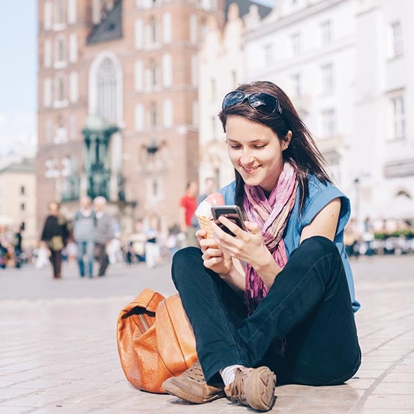 En kvinna som sitter på ett torg i Krakow, flyg till Krakow med Norwegian